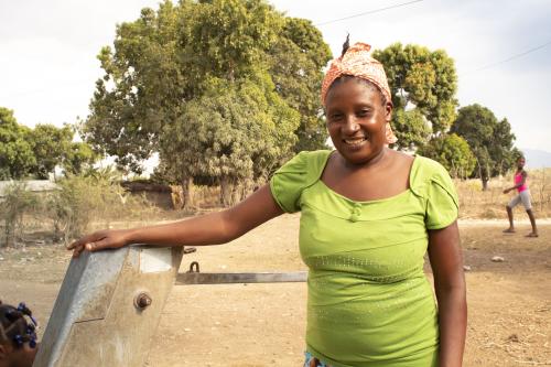 Denise devant un point d'eau été installé avec le financement d’ActionAid